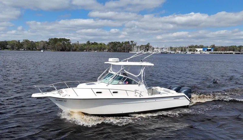 Slide: The Image of 1999 Pursuit 2870 Walkaround boat cruising on a lake under a partly cloudy sky. - 0