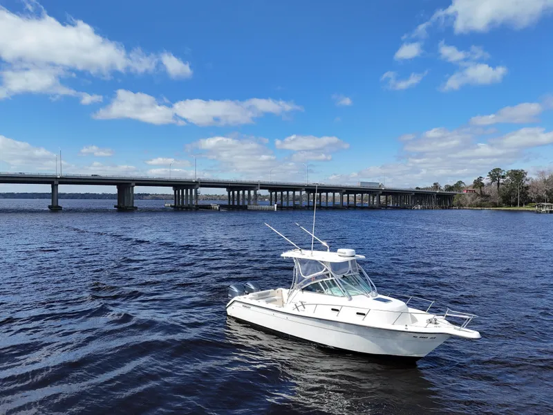 Slide: The Image of 1999 Pursuit 2870 Walkaround boat on a sunny day near a bridge. - 1