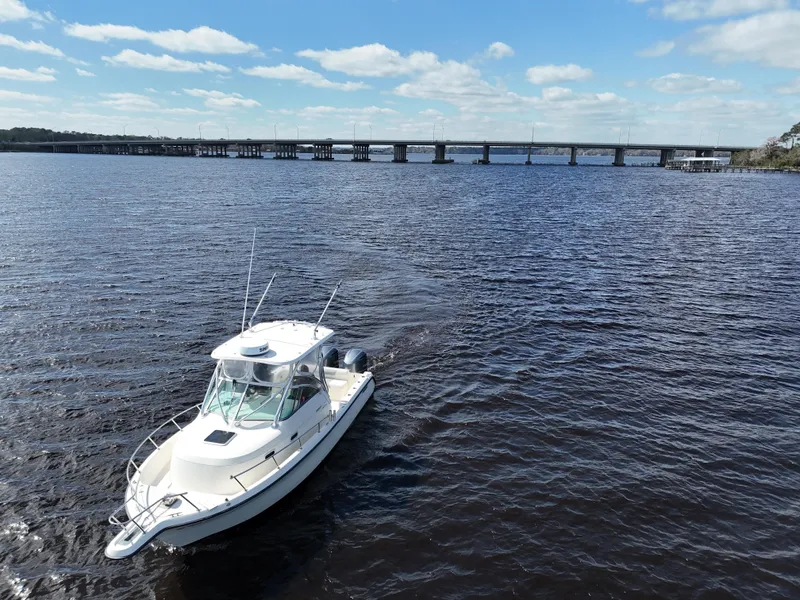Slide: The Image of 1999 Pursuit 2870 Walkaround boat cruising on a sunny day near a bridge. - 10