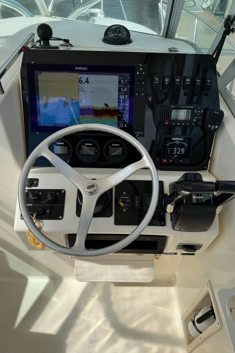 Slide: The Image of 1999 Pursuit 2870 Walkaround boat dashboard with steering wheel and navigation instruments. - 17
