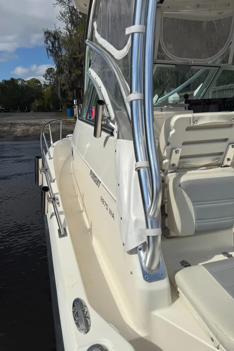 Slide: The Image of 1999 Pursuit 2870 Walkaround boat docked, featuring sleek design and comfortable seating. - 18