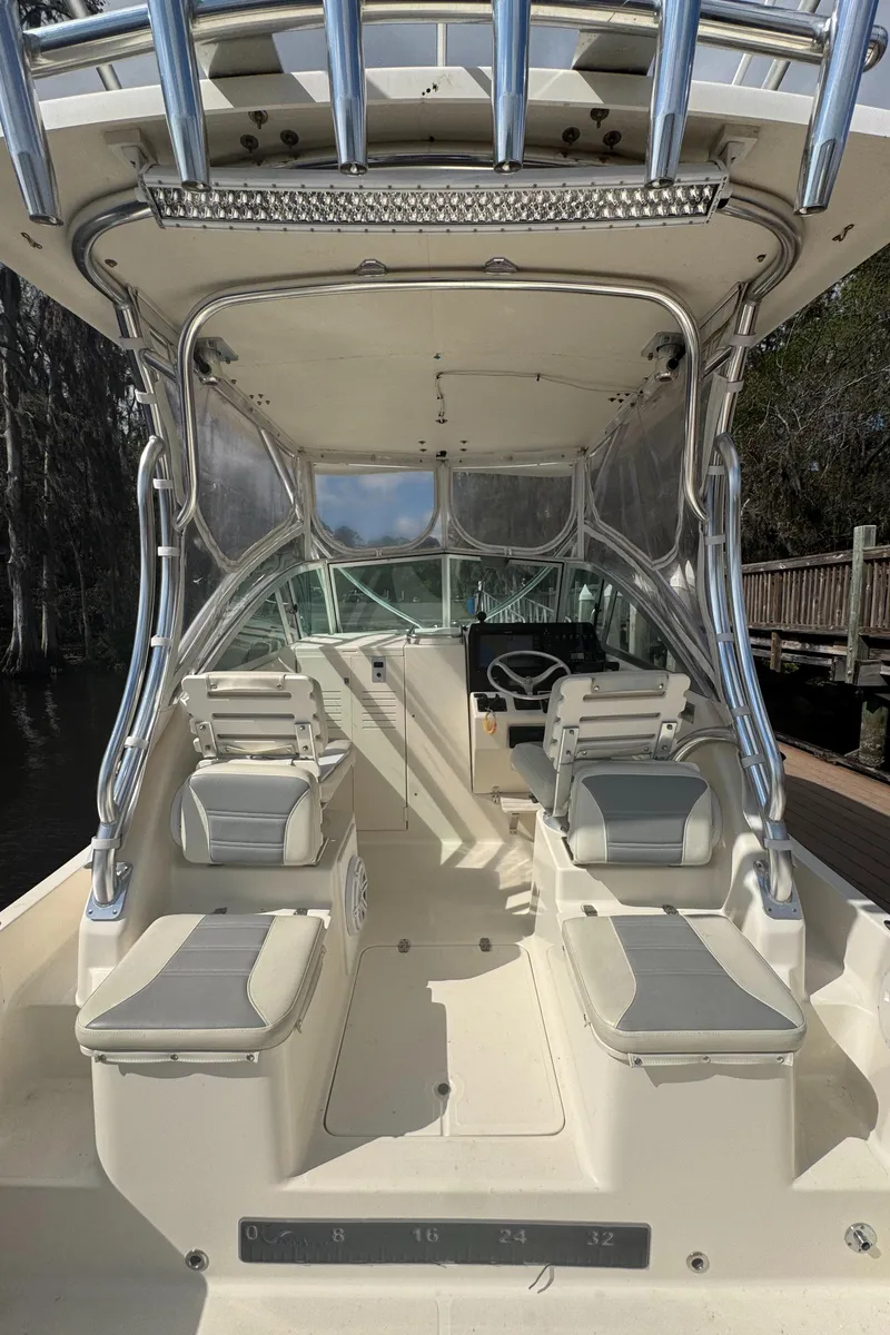 Slide: The Image of 1999 Pursuit 2870 Walkaround boat interior with seating and helm, docked by a wooden pier. - 20