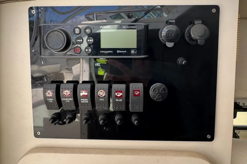 Slide: The Image of Control panel of a 1999 Pursuit 2870 Walkaround boat with switches and radio. - 23