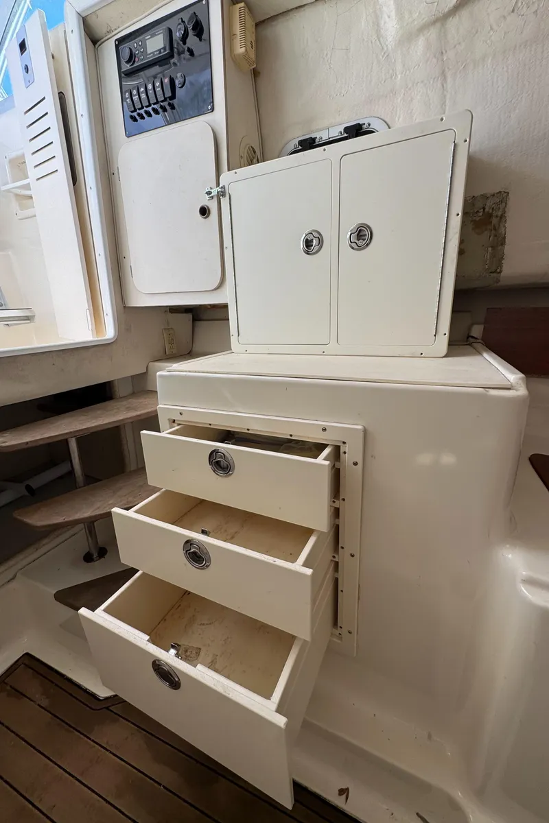 Slide: The Image of 1999 Pursuit 2870 Walkaround boat interior with open storage drawers and control panel. - 24