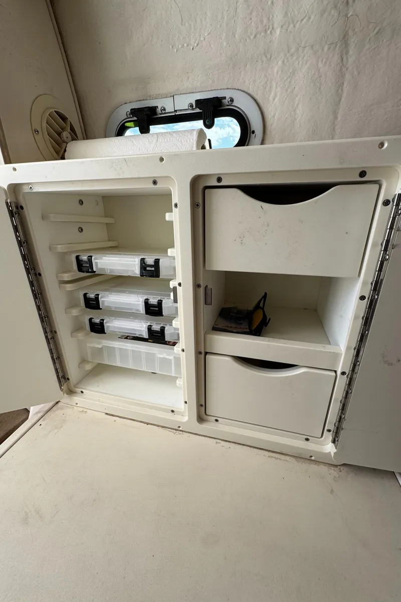 Slide: The Image of 1999 Pursuit 2870 Walkaround boat storage compartment with drawers and shelves. - 25