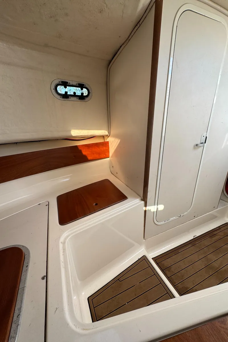 Slide: The Image of 1999 Pursuit 2870 Walkaround cabin interior with wood accents and porthole window. - 26