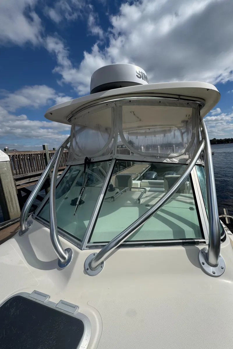 Slide: The Image of 1999 Pursuit 2870 Walkaround boat with radar, docked under a partly cloudy sky. - 27