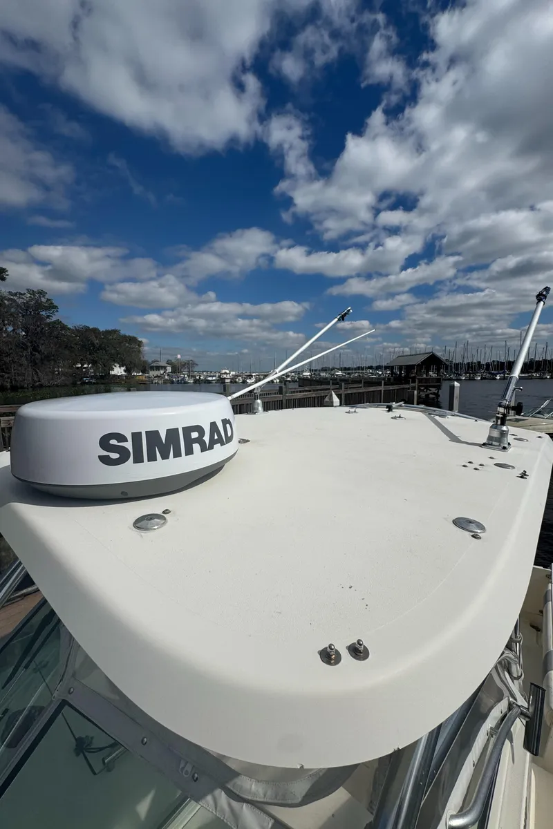 Slide: The Image of 1999 Pursuit 2870 Walkaround boat with Simrad radar under a partly cloudy sky. - 28