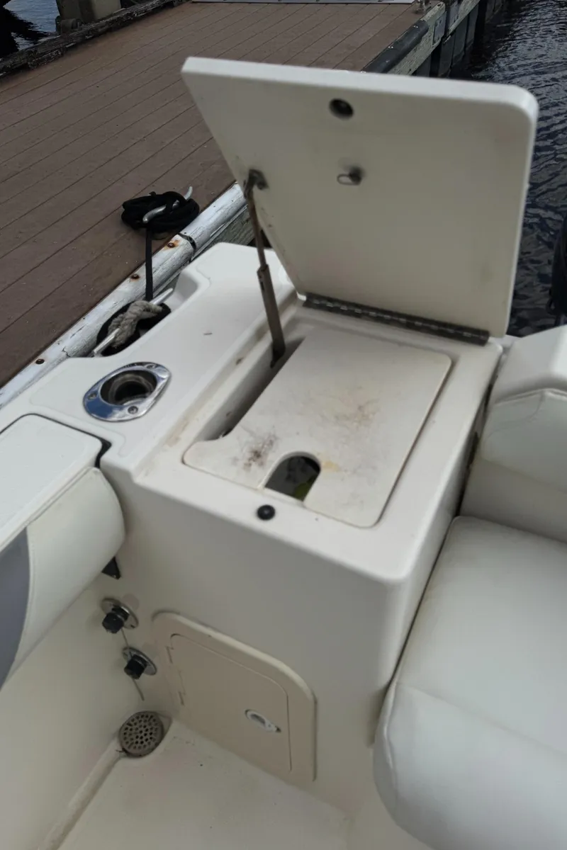 Slide: The Image of 1999 Pursuit 2870 Walkaround boat with open storage compartment near dock. - 36
