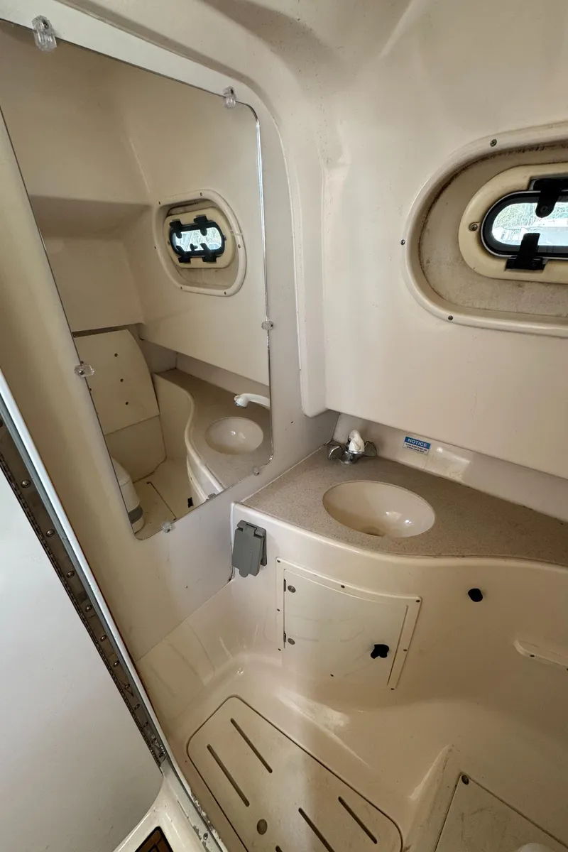 Slide: The Image of 1999 Pursuit 2870 Walkaround boat cabin interior with sink and porthole windows. - 37