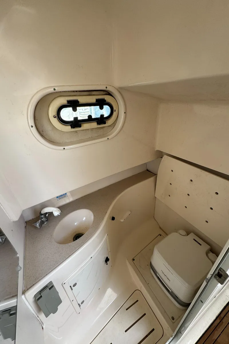 Slide: The Image of 1999 Pursuit 2870 Walkaround boat cabin interior with sink and toilet. - 38