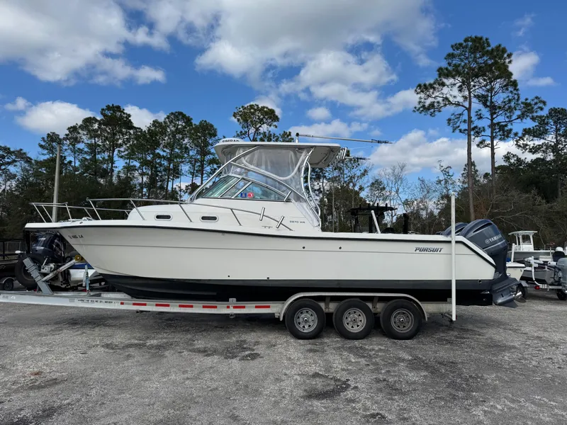 Slide: The Image of 1999 Pursuit 2870 Walkaround boat on a trailer, parked outdoors under a cloudy sky. - 39