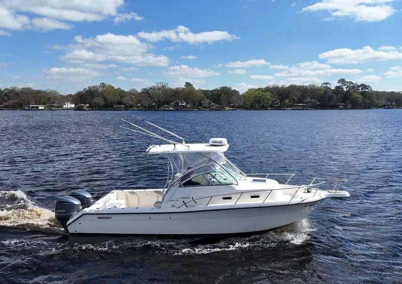 Slide: The Image of 1999 Pursuit 2870 Walkaround boat cruising on a lake under a blue sky. - 6