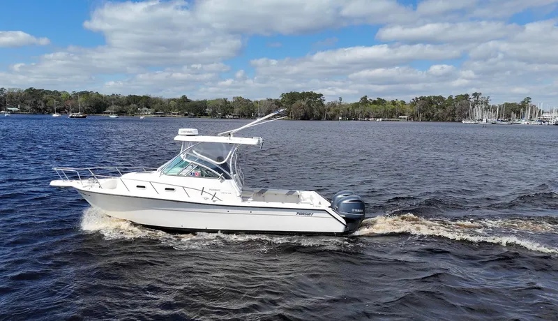 Slide: The Image of 1999 Pursuit 2870 Walkaround boat cruising on a lake under a partly cloudy sky. - 7