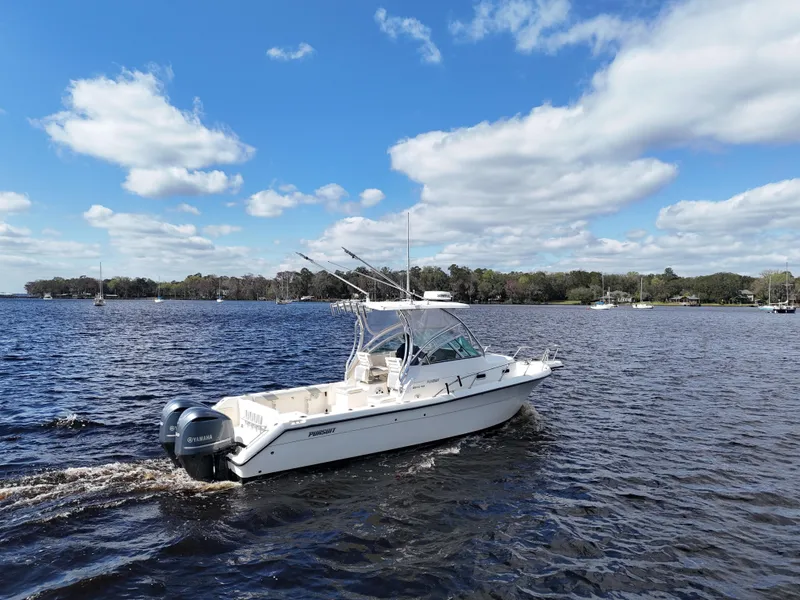 Slide: The Image of 1999 Pursuit 2870 Walkaround boat cruising on a lake under a blue sky. - 8
