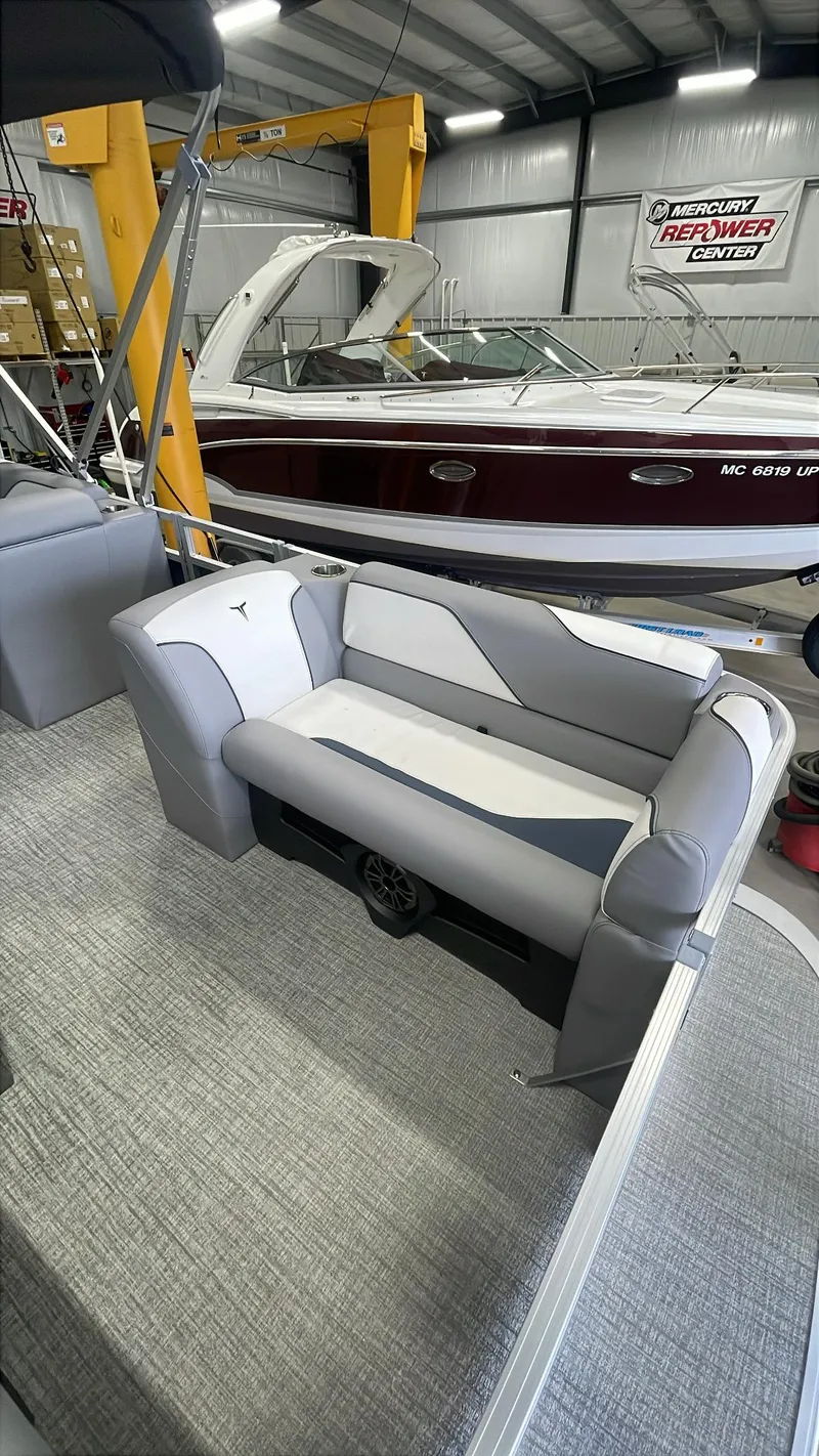 Slide: The Image of 2025 Tahoe Pontoon SP 1980 Quad Lounge interior with gray seating in a showroom. - 10