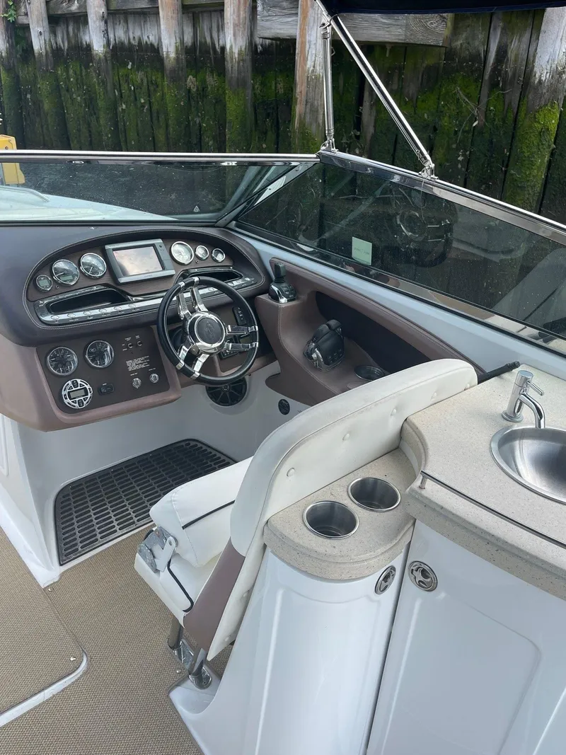 Slide: The Image of 2013 Cobalt 302 boat cockpit with steering wheel, control panel, and sink. - 14