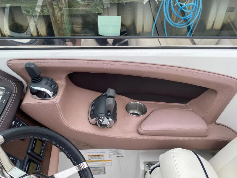 Slide: The Image of Interior of a 2013 Cobalt 302 boat, featuring controls and a cup holder. - 16