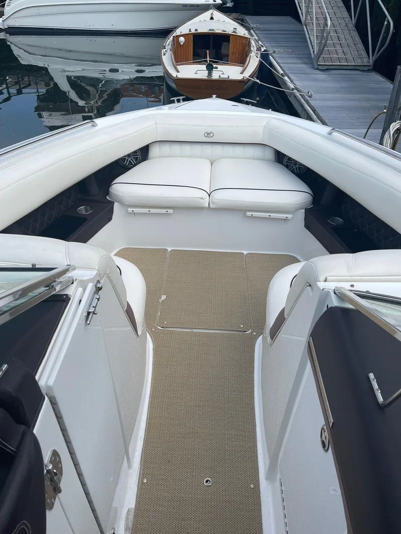 Slide: The Image of 2013 Cobalt 302 boat interior with white seating and beige flooring at a marina. - 19