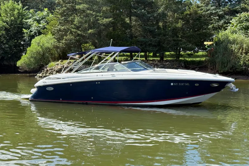 Slide: The Image of 2013 Cobalt 302 boat cruising on a calm river with lush greenery. - 2