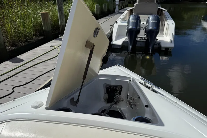 Slide: The Image of Open anchor compartment on 2013 Cobalt 302 boat docked by the water. - 23