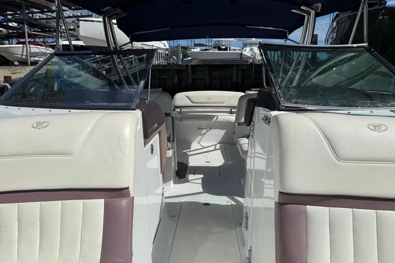 Slide: The Image of 2013 Cobalt 302 boat interior with white and brown seating, docked under blue sky. - 24