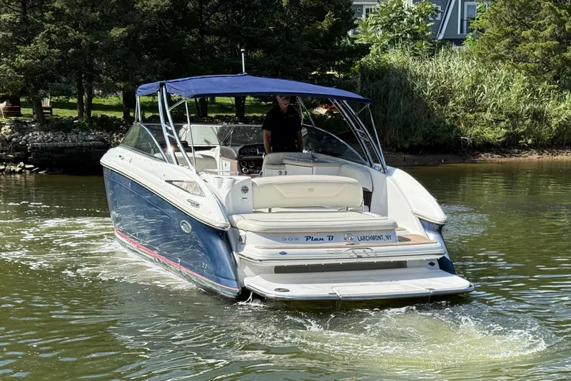 Slide: The Image of 2013 Cobalt 302 boat cruising on a calm river near lush greenery. - 3