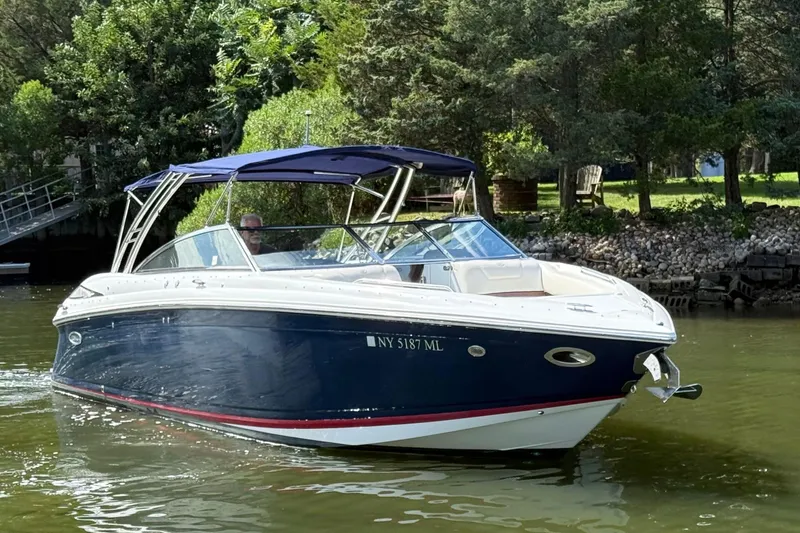 Slide: The Image of 2013 Cobalt 302 boat cruising on a calm lake near a wooded shoreline. - 4