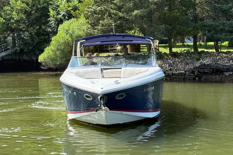 Slide: The Image of 2013 Cobalt 302 boat cruising on a calm river near lush greenery. - 5
