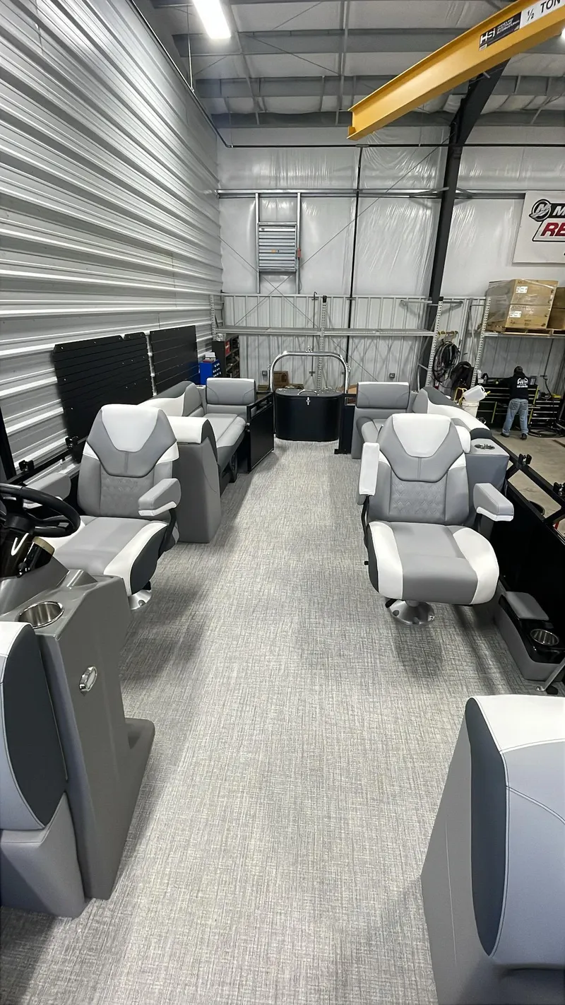 Slide: The Image of 2025 Tahoe Pontoon SP 2385 QL interior with modern seating in a storage facility. - 21
