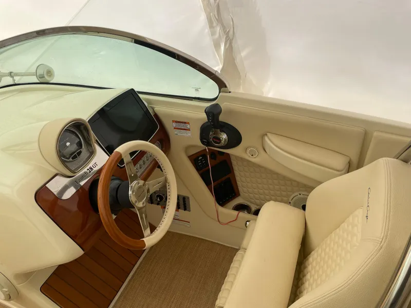 Slide: The Image of 2020 Chris-Craft Launch 28GT cockpit with beige upholstery and wooden accents. - 19