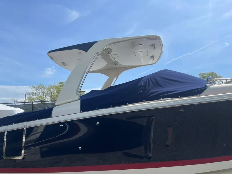 Slide: The Image of 2020 Chris-Craft Launch 28GT boat with blue cover and sleek design under clear sky. - 2