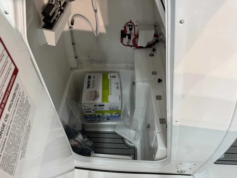 Slide: The Image of 2025 Tidewater 256 CC Adventure boat interior storage compartment with equipment and wiring. - 15
