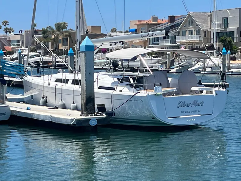 Slide: The Image of 2021 Hanse 418 yacht docked in a marina, surrounded by other boats and waterfront homes. - 14