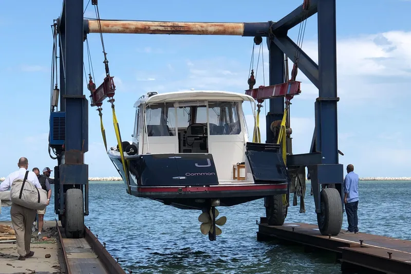 Slide: The Image of A 2005 True North 38 Heritage boat being lifted by a crane at a marina. - 12