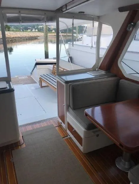 Slide: The Image of Interior of 2005 True North 38 Heritage boat with seating and table, docked by the water. - 16