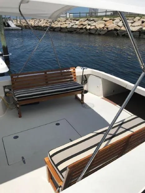 Slide: The Image of 2005 True North 38 Heritage boat with striped seating, docked by a stone-lined waterfront. - 20