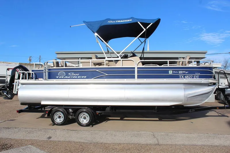 The Image of 2017 Tracker PARTY BARGE® 22 DLX pontoon boat with blue canopy on trailer. - 1