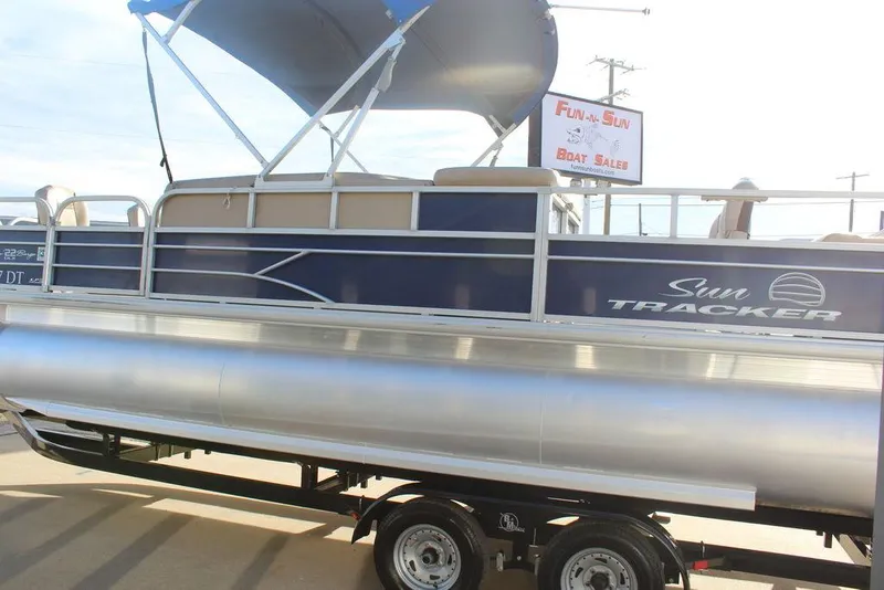 Slide: The Image of 2017 Tracker PARTY BARGE® 22 DLX pontoon boat on trailer, featuring a blue and silver design. - 6