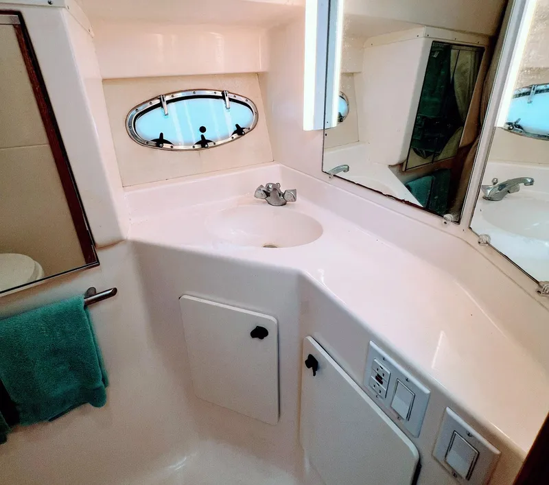 Slide: The Image of 1999 Tiara Yachts 3500 Express bathroom with sink, mirror, and porthole window. - 11