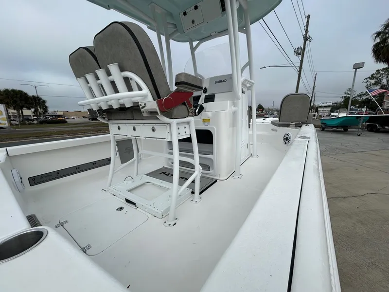 Slide: The Image of 2025 Sea Pro 250 Bay boat interior with seating and console, parked outdoors. - 5