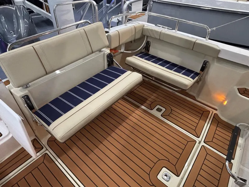 Slide: The Image of 2025 Ranger Tugs R-23 boat interior with cushioned seating and teak flooring. - 10