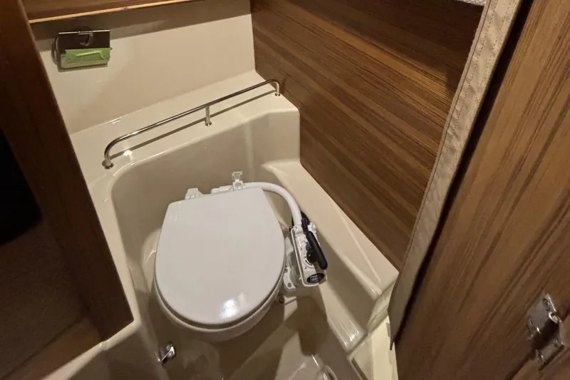 Slide: The Image of 2025 Ranger Tugs R-23 boat bathroom with compact toilet and wooden paneling. - 18