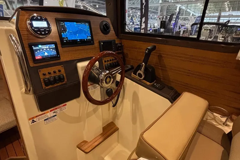 Slide: The Image of 2025 Ranger Tugs R-23 helm with navigation screens and wooden steering wheel. - 7