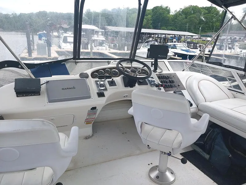 Slide: The Image of 1997 Sea Ray 370 Aft Cabin helm with Garmin navigation, white seating, and marina view. - 2