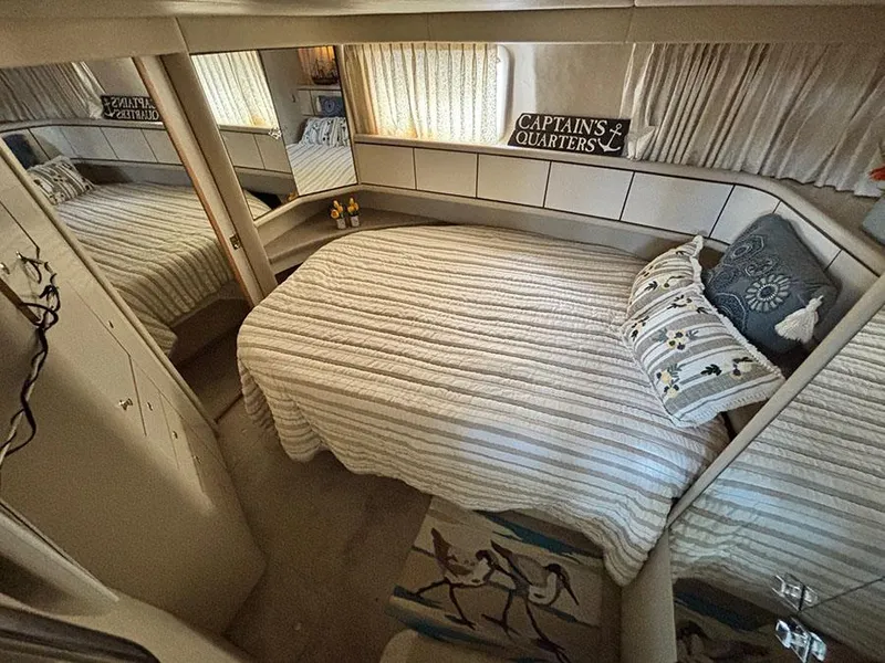 Slide: The Image of 1997 Sea Ray 370 Aft Cabin bedroom with cozy bed, nautical decor, and mirrored closet. - 42