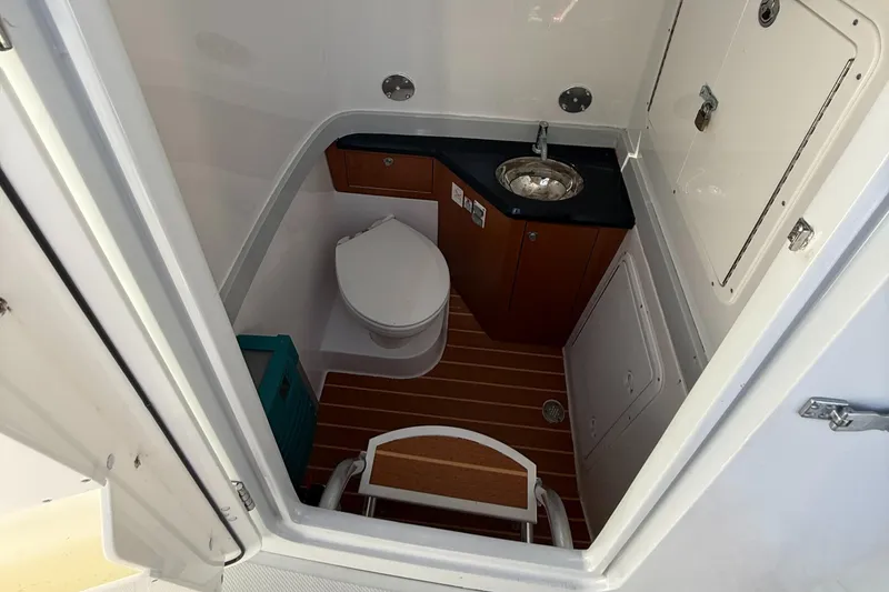 Slide: The Image of 2018 Bluewater Center Console boat bathroom with toilet, sink, and wooden flooring. - 15