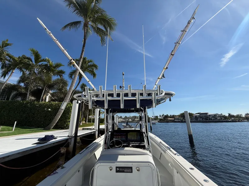 Slide: The Image of 2018 Bluewater Center Console boat docked by palm trees and waterfront homes. - 2
