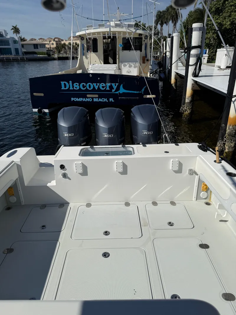Slide: The Image of 2018 Bluewater Center Console boat with triple engines docked near "Discovery" yacht. - 6