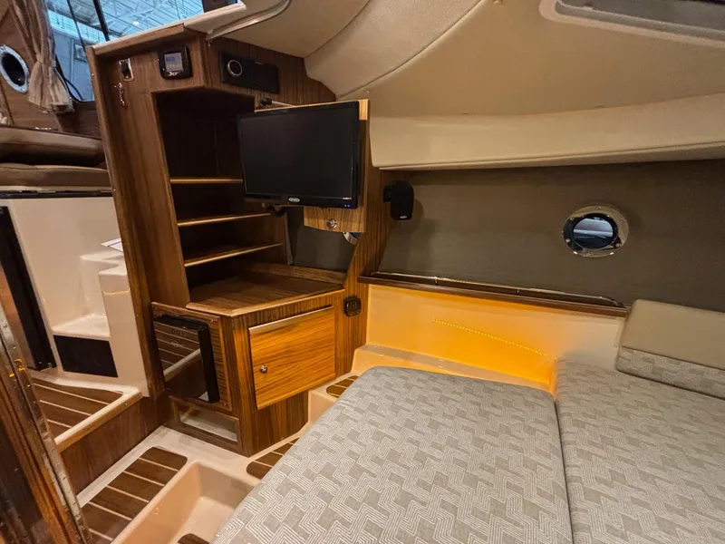 Slide: The Image of 2025 Ranger Tugs R-29 S interior cabin with wood finish, TV, and cozy seating. - 19